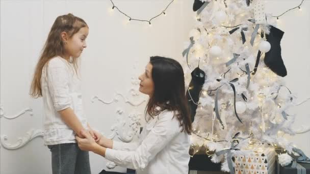 Neşeli anne ve kız güzel süslenmiş Noel ağacının yanında sarılıyorlar.. — Stok video