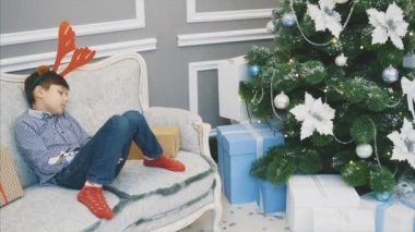 Ren geyiği başlıklı küçük çocuğun Noel hediyesi olarak Noel ağacının yanındaki kanepede uyuduğu sevimli bir video..