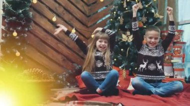4k video 'da küçük bir çocuk ve kız gülüyor, ellerini kaldırıyor, yılbaşı ağacının yanındaki gizemli ışığa bakıyor..
