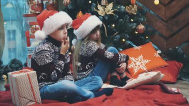 Ağabeyi Noel hediyesi kutusunu kız kardeşine verirken çekilmiş 4k 'lik güzel bir video. Ağacın yanında otururken..