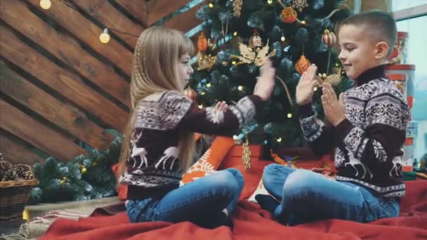 4k Video von Jungen und Mädchen, die lachen, zusammen Spaß haben, ein Klatschspiel vor einem hölzernen Weihnachtshintergrund spielen. — Stockvideo