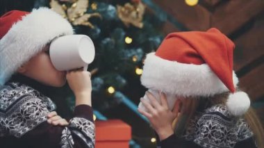 Mutlu ikizler Noel arifesinde kakao içiyorlar ve sonra başparmaklarını kaldırıyorlar, gerçekten lezzetli olduğunu gösteriyorlar..