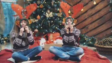 Sevimli küçük çocuklar ren geyiği boynuzlarından başlık takıp yılbaşı akşamı surat asıyorlar..