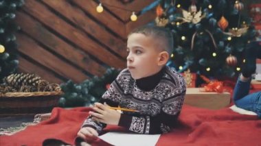 Düşünceli bir çocuğun Noel Baba 'ya yazacak bir şey ararken 4K videosu..