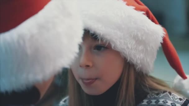 4k cultivo de vídeo de los niños con mentalidad de usar sombreros de santa en Nochebuena, beber cacao caliente y preguntarse acerca de lo que van a recibir como un regalo . — Vídeo de stock