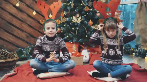 Lindo video de 4k de hermano y hermana poniéndose cuernos de reno y posando en la cámara en la noche de Navidad . — Vídeo de stock