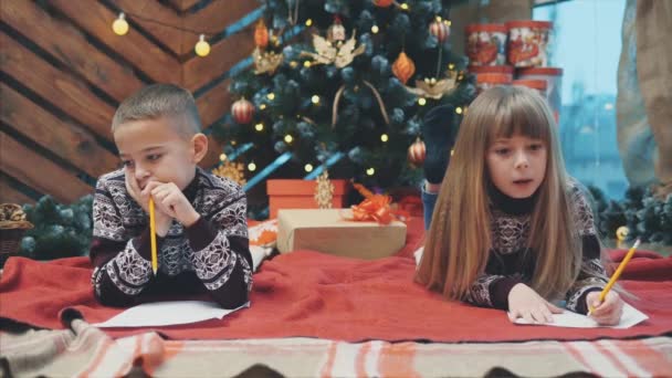 4k video von bruder und schwester unter dem weihnachtsmailing weihnachtsmann, schreiben lieber santa ich war gut und ich wünsche.... — Stockvideo