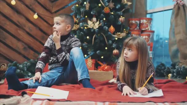 Broers en zussen onder Kerstmis schrijven verlanglijstje naar de Kerstman, uiteindelijk perfect idee gekruist jongens geest. — Stockvideo