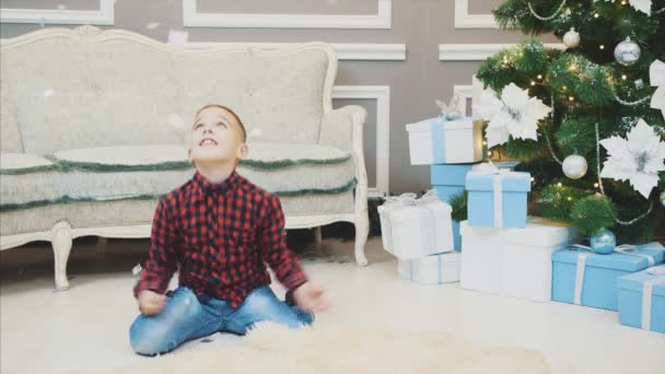 4k video van een jongen kotsen tinsel en confetti, lachen, kijken opgewonden. — Stockvideo