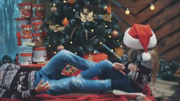 Bambini divertenti attivi che giocano tra loro, spingendo i piedi, sul tappeto vicino all'albero di Natale . — Video Stock