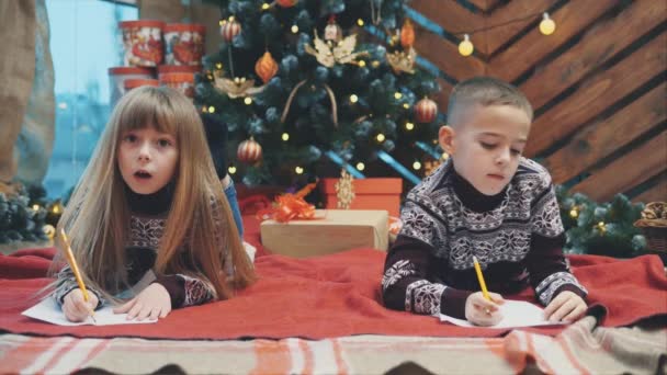 サンタクロースにメールを送るクリスマスの下で兄弟姉妹の4kビデオ、親愛なるサンタ私は良かったと私は願っています.... — ストック動画
