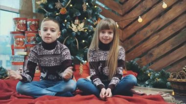 Bordo yünlü süveter giyen beyaz kardeşler yeni yıl atmosferinden memnunlar ve başparmaklarını gösteriyorlar..