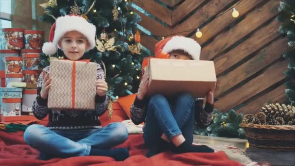 Hijo e hija prepararon regalos de Navidad para sus padres y los están mostrando a la cámara, luciendo orgullosos de lo que han hecho . — Vídeos de Stock