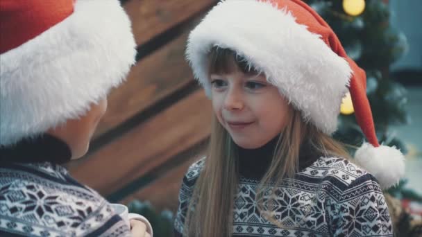 Ralenti recadré de bébé drôle dans le chapeau de Père Noël, avec rire de génie maléfique, en regardant son frère avec expression faciale comme si elle pensait quelque chose de mauvais . — Video