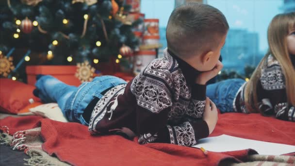 Kleine blonde broertjes en zusjes zijn er zeker van dat ze zich het hele jaar goed hebben gedragen en nu schrijven ze een brief aan de Kerstman om het cadeau te krijgen.. — Stockvideo