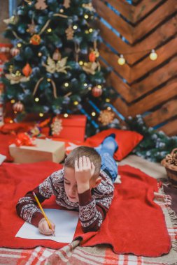 Bütün yıl uslu durduğundan emin olan küçük çocuk hediyesini almak için Noel Baba 'ya mektup yazıyor..