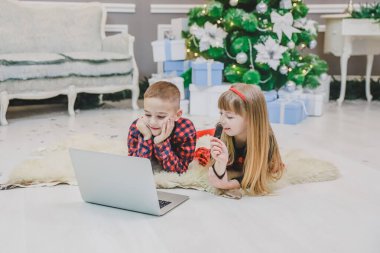 Neşeli çocuklar dizüstü bilgisayarlarında yeni yıl için dekore edilmiş modern oyunlar oynuyorlar..