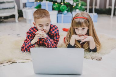 Neşeli çocuklar dizüstü bilgisayarlarında yeni yıl için dekore edilmiş modern oyunlar oynuyorlar..