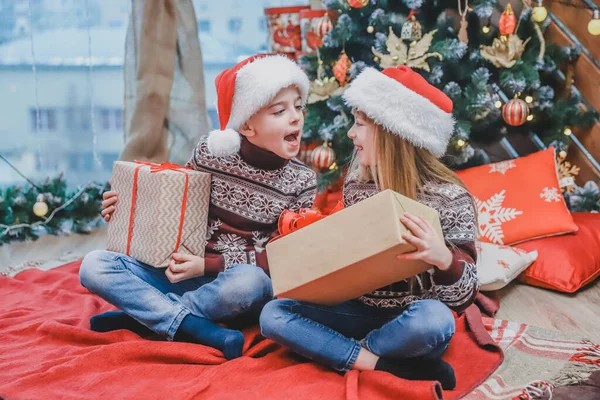 Los niños vestidos de Papá Noel se están burlando unos de otros, compitiendo cuyo presente es mejor . — Foto de Stock