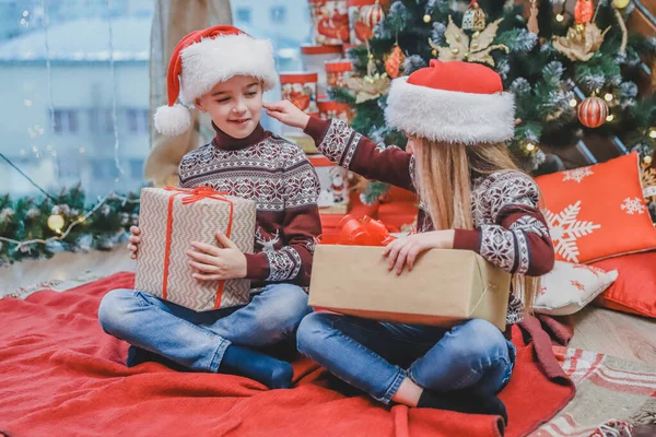 Los niños vestidos de Papá Noel se están burlando unos de otros, compitiendo cuyo presente es mejor . — Foto de Stock