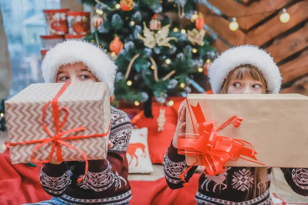 Närbild foto av son och dotter som förberett julklappar till sina föräldrar och visar dem för kameran, ser stolta över vad de har gjort. — Stockfoto