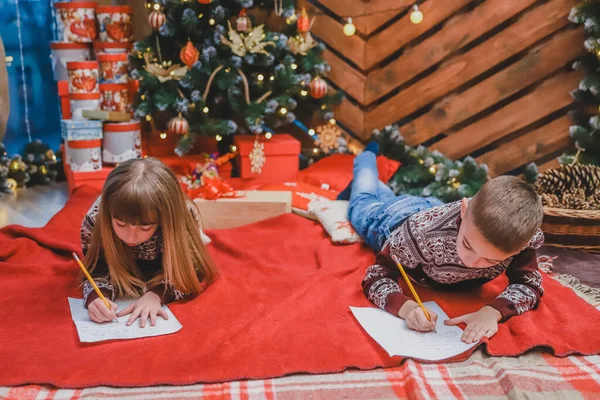 Um tiro do irmão e da irmã sob o Natal que envia o Papai Noel, escrevendo Caro Papai Noel eu era bom e eu desejo .... — Fotografia de Stock