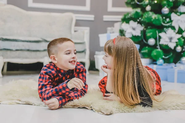 Lindo poco pasar tiempo agradable juntos, la comunicación en la alfombra cerca del árbol de Navidad . — Foto de Stock