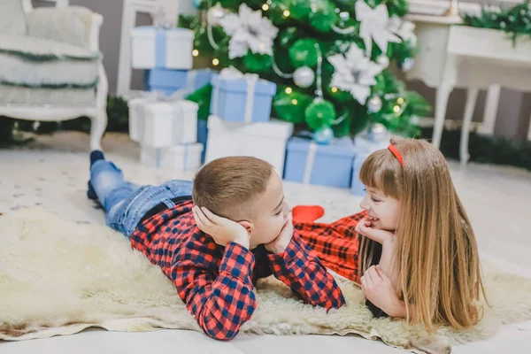 Cute little spędzić przyjemny czas razem, komunikując się na dywanie w pobliżu choinki. — Zdjęcie stockowe