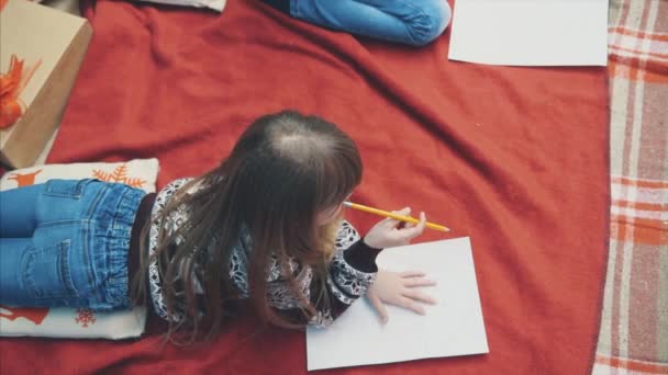 Top-view αργή κίνηση του ξανθού κοριτσιού που σκέφτεται τι να γράψει στο γράμμα προς Nord Pole, που βρίσκεται σε κόκκινη κουβέρτα το βράδυ του χειμώνα. — Αρχείο Βίντεο