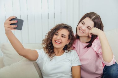 Kanepede oturan, selfie çeken, poz veren, gülümseyen tatlı genç kızlar..