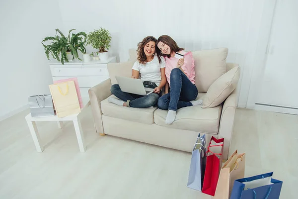 Zwei glückliche Freundinnen mit Laptop online einkaufen. Ein Mädchen hält eine Kreditkarte. sie wählen Kleidung. — Stockfoto
