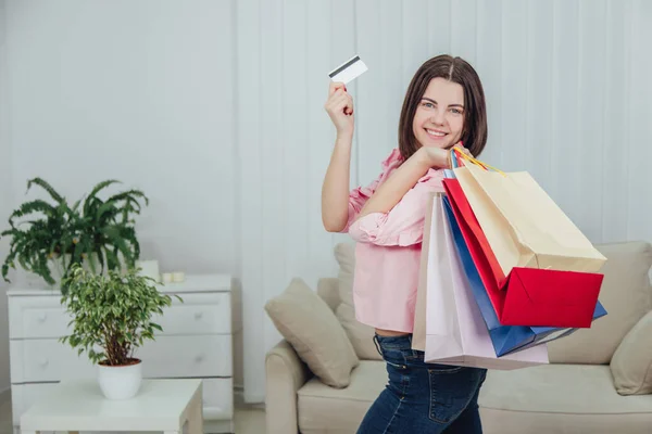 Young caucasian girl is standing with a lot of bags from shop in her hands, looking at the camera with excited face expression. — Stock Photo, Image
