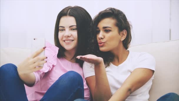 Lindas novias jóvenes sentadas en el sofá, tomando selfie, posando, sonriendo . — Vídeos de Stock