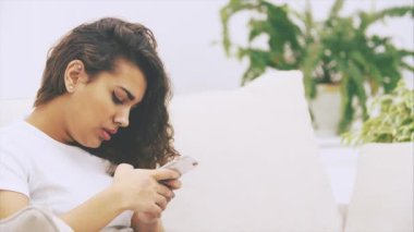 Sevimli Afro-Amerikalı kız koltukta oturuyor, elinde telefonla, mesajlar yolluyor..