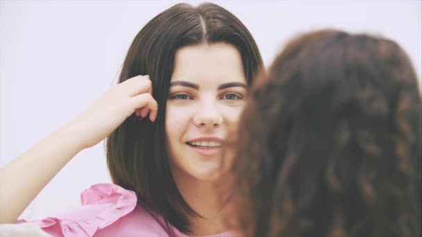 Happy friends talking carelessly, laughing, sitting on the sofa. Afro-american kinky girl, sitting back to the camera, blurred. — Stock Video