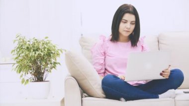 Loto pozisyonunda kanepede oturan, dizüstü bilgisayarı olan, internette sörf yapan, duygusal davranan beyaz tenli tatlı kız..