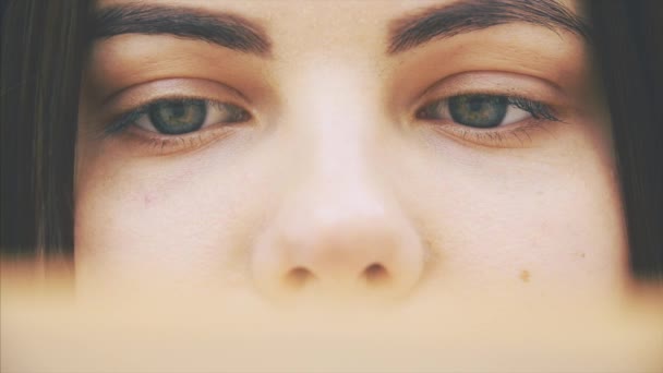 Rostro recortado de una joven curiosa leyendo un libro, moviendo los ojos hacia adelante y hacia atrás a lo largo de la página . — Vídeo de stock