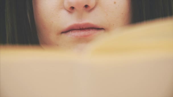 Nyfiken ung kvinna läser en bok, ser helt engagerad och upphetsad ut. Kameran rör sig uppåt. — Stockvideo