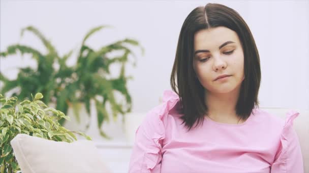 Zvídavá mladá žena sedí na pohovce, v lotosové poloze, čte knihu a emocionálně reaguje na zápletku. — Stock video