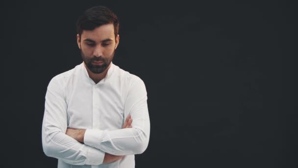 Joven hombre confiado en camisa blanca, de pie sobre el fondo negro, posando, con las manos dobladas . — Vídeos de Stock