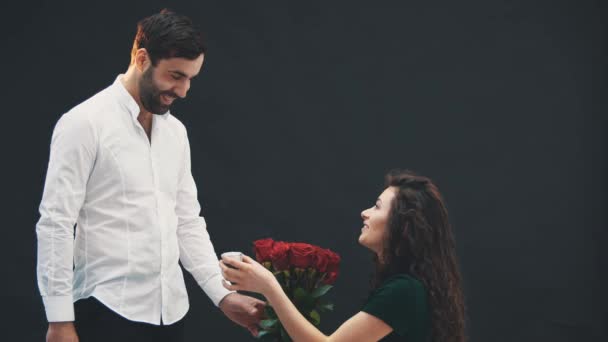 Смішна дивна жінка стоїть на одному коліні з кільцем і трояндами в руках, роблячи пропозицію свого чоловіка. Він каже "так". Вони цілуються . — стокове відео