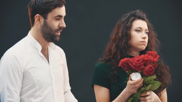 Schattige kinky vrouw geeft man ring en rozen en dwingt hem om haar aanzoek te doen. Hij wil het niet doen.. — Stockvideo