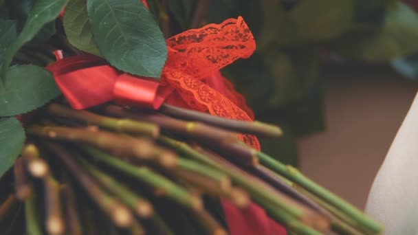 Vídeo recortado de ramo de rosas rojas grandes. Concéntrate en la cinta roja atada con un bonito nudo . — Vídeo de stock