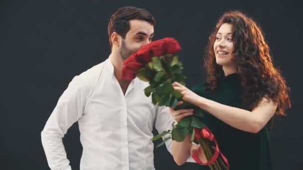 Забавная пара играет вокруг, танцуя с букетом роз, двигая бедрами и руками. Мужчина подбирает свою женщину и выполняет . — стоковое видео