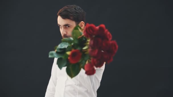 Divertente giovane che scherma con un mazzo di rose rosse come se fosse spada. Poi lo annusa, lo mette sulla spalla, se ne va . — Video Stock