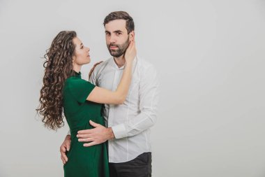 Tatlı bir çift, yakışıklı bir adam ve sapkın bir kadın, beyaz arka planda sarılıyorlar..