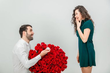 Erkek, eşine nişan yüzüğü ve bir demet kırmızı çiçek vererek evlenme teklif eder, kadın şaşırır..