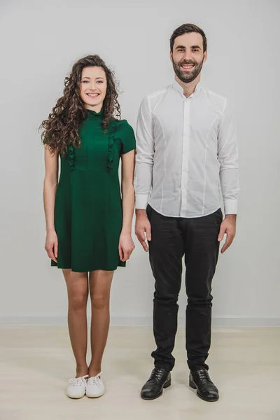 Portret pięknej młodej pary stojącej obok siebie i uśmiechającej się do kamery odizolowanej na białym tle. — Zdjęcie stockowe