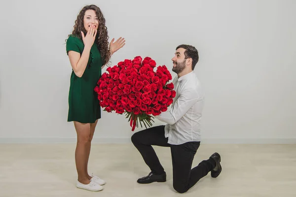 Man frågar partner att gifta sig med honom genom att ge henne en förlovningsring och en massa röda blommor, kvinna är häpen. — Stockfoto