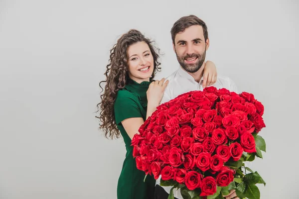Szczęśliwa elegancka para przytula się i uśmiecha, na białym tle. Człowiek trzyma róże.. — Zdjęcie stockowe